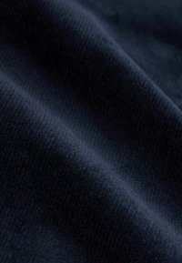 Tissu bleu marine avec une surface douce et texturée. Le matériau présente un motif côtelé, montrant de légères variations de lumière et d'ombre.