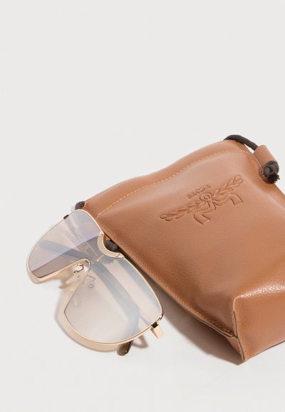 Διαφανή φιμέ γυαλιά τύπου aviator με χρυσά πλαίσια δίπλα σε καφέ δερμάτινο πουγκί με κορδόνι, διακοσμημένο με ανάγλυφο σχέδιο δάφνης και κορδέλας.