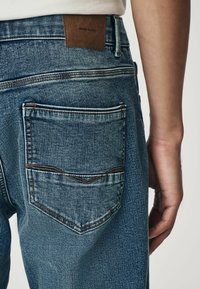 Lichtblauwe denim jeans met een gestructureerde afwerking. Voorzien van een leren label met de tekst "DENIM SUPPLY" en een dubbel gestikte achterzak.