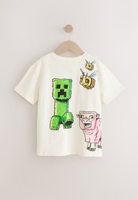 Cremefarbenes Baumwoll-T-Shirt mit Cartoon-Grafiken: eine grüne Blockfigur, rosa und schwarze Schafe sowie zwei gelb-schwarze Bienen. Kurze Ärmel.