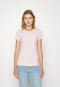 Šviesiai rožinė medvilninė marškinėliai su apvalia apykakle ir trumpomis rankovėmis. Krūtinėje yra baltas "Pepe Jeans London" logotipas.