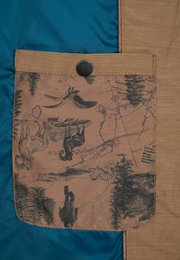 Poche en tissu marron avec bouton-pression noir sur un matériau bleu et beige, avec imprimé vintage de la faune et une carte avec des animaux et des arbres.