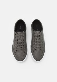 Baskets en cuir gris présentant une forme arrondie, un avant à lacets et une semelle en caoutchouc blanc. Texture lisse avec un minimum de détails.
