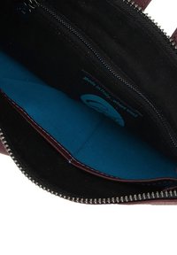 Interno della borsa color bordeaux con foderatura nera, un compartimento blu brillante e una zip con hardware argentato. Etichetta che recita "Made in Italy."