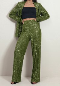 Ensemble à deux pièces vert en sequins, comprenant un haut court ajusté et un pantalon large, fabriqué dans un matériau texturé avec une finition brillante.