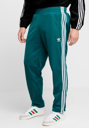 Teal trainingsbroek met witte zijstrepen, voorzien van een elastische tailleband, een zip-pocket en een geborduurd logo op de linker dij.