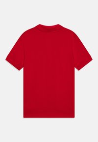 Rdeča kratkodela majica polo iz gladkega bombažnega blaga ima klasičen ovratnik ter čiste robove na rokavih in spodnjem delu.