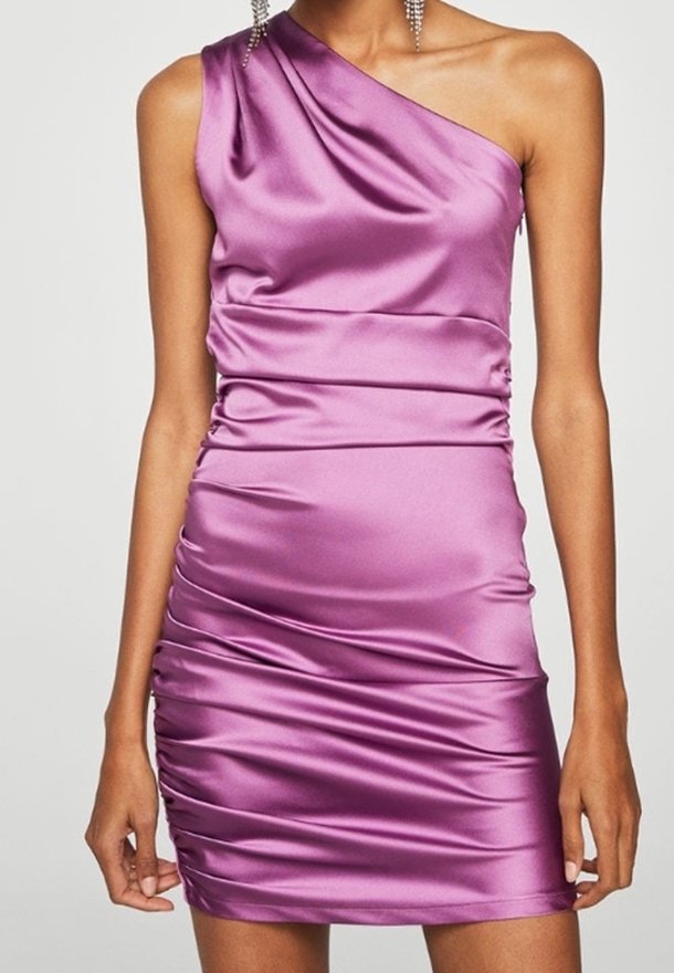 Femme portant une mini-robe en satin violet brillante, froncée, à une épaule, avec de longues boucles d'oreilles pendantes.