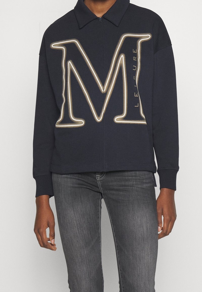 Felpa zip con cappuccio di colore blu navy, decorata con una grande lettera "M" a contorno dorato e la scritta "LEISURE". Presenta un colletto e polsini a costine.