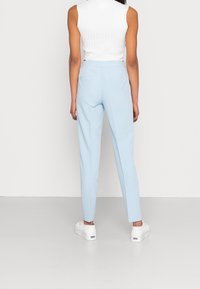 Ljusblå skräddarsydda byxor med smal passform, med två bakfickor. Kombineras med vita platåskor och en ribbad vit topp.