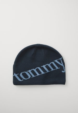Knitted beanie in dark navy with light blue "tommy" logo. Soft texture, fitted shape, and seamless design for warmth and comfort.