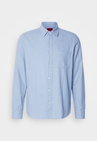 Chemise bleu clair à manches longues, boutonnée, avec col et poche poitrine comportant un petit logo "Hugo".