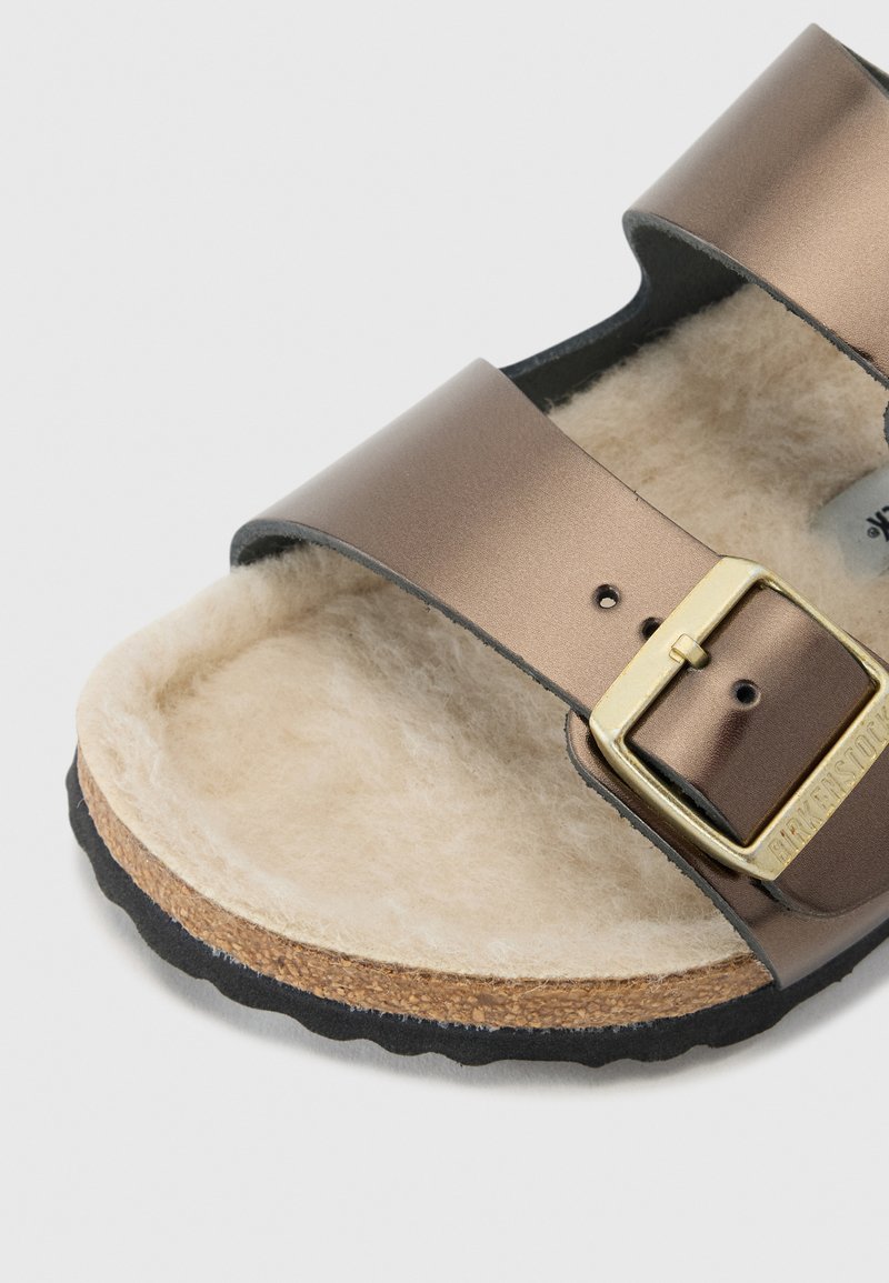 Sandale de style Birkenstock marron avec deux sangles métalliques ajustables, doublure intérieure douce et semelle en liège. Détail de boucle sur la sangle.