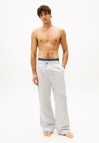 Witte en blauwe gestreepte pyjamabroek met een elastische tailleband, voorzien van een "Tommy Hilfiger" logo, relaxte pasvorm en zachte stoftextuur.
