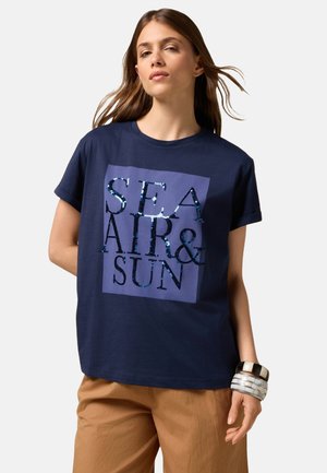 T-shirt en coton bleu marine à manches courtes, avec un motif en sequins bleu clair et noir sur un carré violet portant l'inscription "MER AIR & SOLEIL".