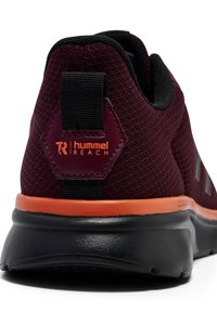 Baskets de sport bordeaux avec une tige en maille, un onglet au talon noir et un accent orange le long de la semelle. Présente un détail de marque hexagonal.