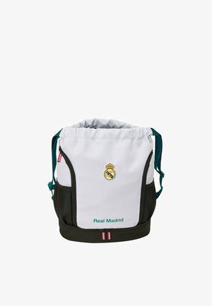 Biała i czarna torba sportowa Real Madrid z górnym ściągaczem, przednimi kieszeniami na zamek, bocznymi kieszeniami z siatki oraz zielonymi paskami na ramię.