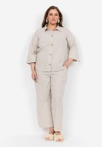 Stribet, beige to-delt outfit med trekvart ærmer, knaplukning fortil og elastisk talje. Har slippers med blomsterdetaljer.