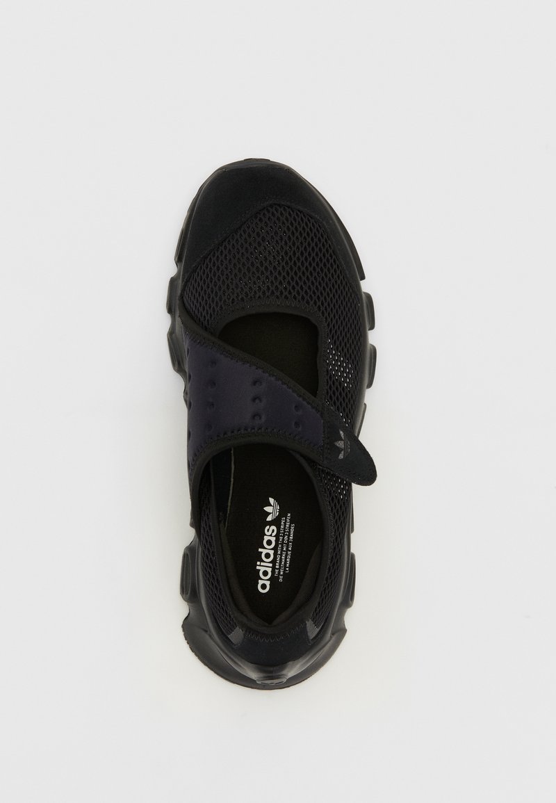 Chaussure de sport noire avec tige en mesh, sangle réglable et semelle en caoutchouc. Caractéristiques de la marque adidas sur la semelle intérieure. Bout arrondi et design basse.