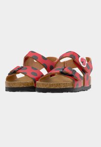 Κόκκινα παιδικά σανδάλια με μαύρα πουά, ρυθμιζόμενα λουριά με μαύρη αγκράφα, πάτους από φελλό και διακοσμητικά πασχαλίτσες στα λουριά του αστραγάλου.