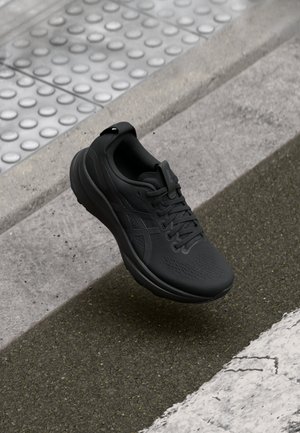 Black running shoe with a breathable mesh upper, textured surface, and a cushioned sole. Features laces and a heel tab for easy wear.