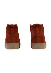 Botas de tobillo de ante rojo con puntera redondeada, costuras visibles y suelas de goma beige. Incluyen una pestaña en la parte trasera para facilitar su uso.