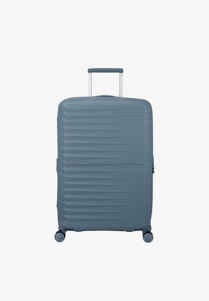 Valigia rigida blu chiaro con texture a righe orizzontali, manico retrattile e quattro ruote piroettanti per una manovrabilità facile.
