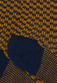 Tessuto lavorato a maglia in blu navy e giallo senape, con un motivo testurizzato. Include polsini blu navy solidi con finitura a coste.