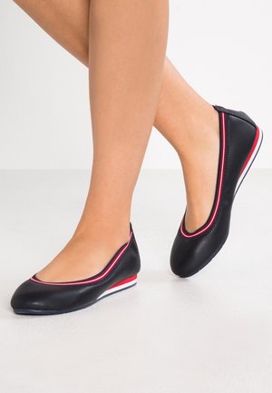 Schwarze Ballerinas mit einer glatten Lederoberfläche, die rote und weiße Akzente entlang der Kanten und eine niedrige, flexible Sohle aufweisen.