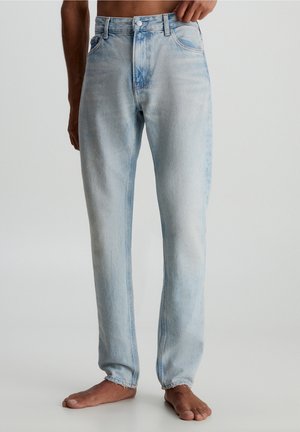 Jeans de denim azul claro con un diseño de pierna recta, que presentan un cierre de botones, cinco bolsillos y un detalle deslavado en la tela. El dobladillo tiene un acabado deshilachado.