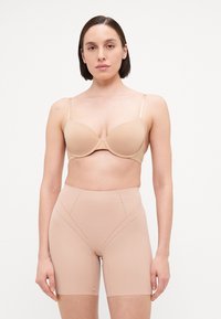 Beige uitneembare beha met verstelbare bandjes en bijpassende hooglopende shaping shorts met geperforeerde details en een gladde textuur.
