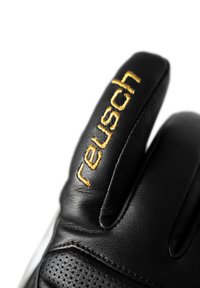 Sort læderhandske med gul "reusch" broderi, der har perforerede detaljer og en glat tekstur på håndfladen og fingrene.