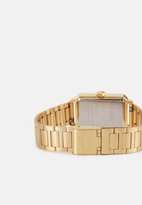 Gold metal wristwatch with a rectangular face and a link bracelet. The band features flat and polished segments, and a clasp marked "CLUSE."