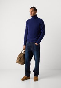 Marinefarbener Rollkragenpullover, lockere blue Jeans, beigefarbene Wildlederschuhe und eine braune Lederhandtasche. Glatte Textur und schlichte Designelemente.