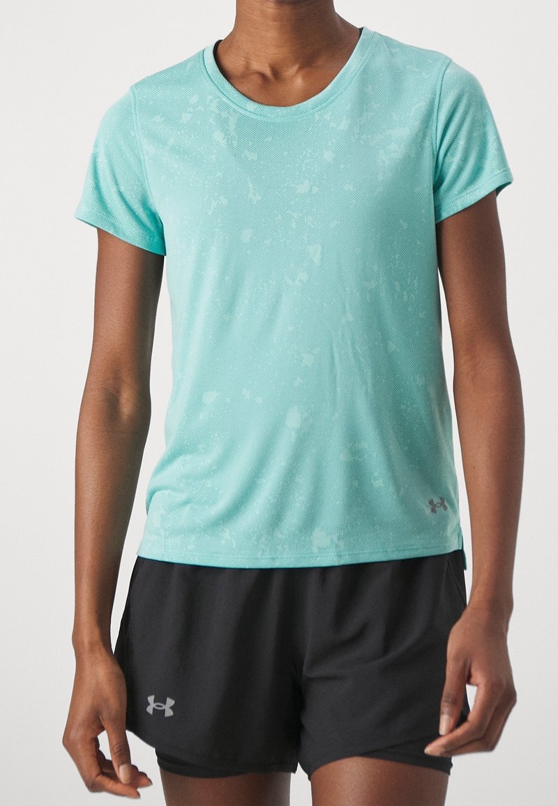 Camiseta atlética turquesa de manga corta, con tejido texturizado y un ligero patrón salpicado, combinada con pantalones cortos negros que presentan un acento de logo en el dobladillo.