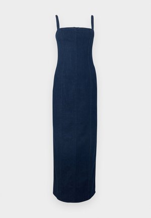 Robe midi en denim bleu foncé avec fines bretelles, dotée de coutures verticales ; associée à des chaussures slip-on à imprimé léopard et une pochette à motifs.
