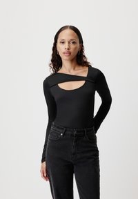 Černý bodysuit s dlouhými rukávy, širokým čtvercovým výstřihem a výřezem. Vhodný k černým džínům s vysokým pasem. Hladká textura.