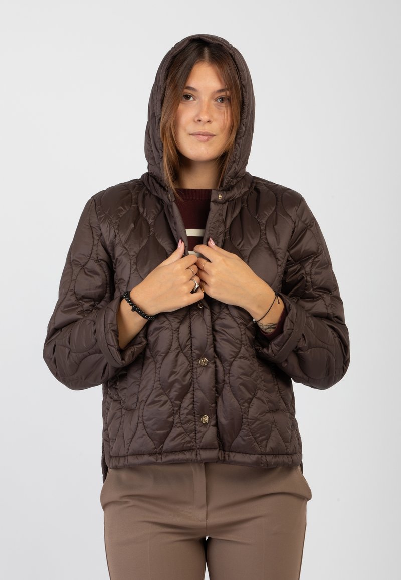 Giubbotto marrone trapuntato con cappuccio, caratterizzato da una trama uniforme e bottoni a pressione sul davanti. Il design include una vestibilità leggermente accorciata e tasche laterali.