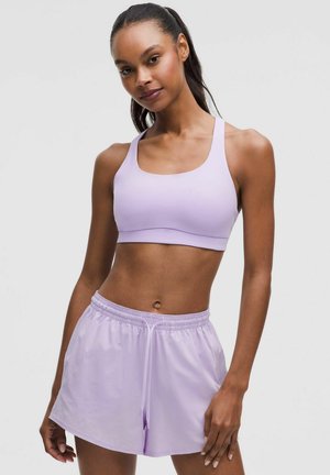 Ljuslila sport-bh med breda band, tillsammans med matchande lila shorts med elastisk midja och snörning.