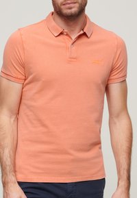 Korte mouwen polo shirt in koraaloranje, gemaakt van zachte katoen. Bevat een kraag, een twee-knopen sluiting en subtiele logo borduring.