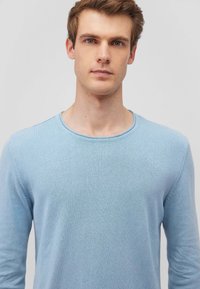 Himmelblaues, langärmliges Sweatshirt mit Rundhalsausschnitt, aus einem glatten Strickstoff gefertigt. Verfügt über dezente Nähte entlang der Ärmel.