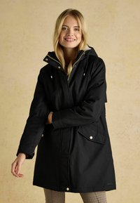 Schwarze wasserdichte Parka mit Kapuze, goldenen Hardwareelementen, Reißverschluss vorne und Seitentaschen, mit lockerem Schnitt und langen Ärmeln.