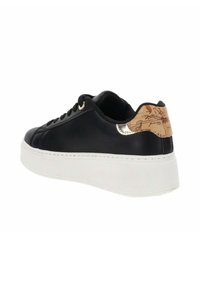 Zapatilla negra de cuero con una gruesa suela blanca de plataforma, ojales dorados y un talón texturizado en tono marrón con un diseño de mapa.