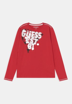 Rotes Langarmshirt mit weißem und schwarzem abstraktem "GUESS EST. 81" Textdesign auf der Brust und weißen Steppnähten an Schultern und Manschetten.