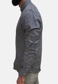 Camicia con bottoni caratterizzata da un motivo geometrico blu navy e bianco, maniche lunghe e colletto classico. Realizzata in cotone con una texture liscia.