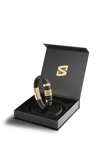 Black leather bracelet with gold-tone accents, featuring textured gold sections. Displayed in a black gift box with a soft inner lining.