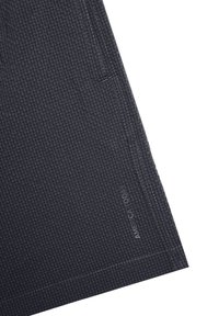 Tummanharmaat haarat, jotka on valmistettu teksturoituneesta kankaasta, jossa on ruudullinen kuvio, sivutasku ja "AMERICA TODAY" -teksti lähimpänä helmaa.