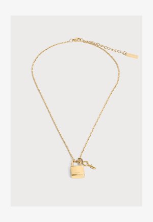 Collier chaîne en or avec petit cadenas et pendentif clé, avec logo Lacoste et fermoir ajustable avec étiquette de marque.