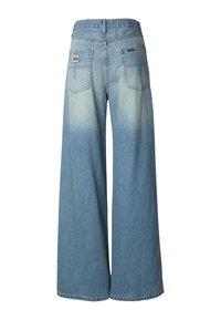 Modre kavbojke širokih hlačnic z izpranim videzom, z dvema zadnjima žepoma in logotipom na pasu. Čist rob hlačnic.
