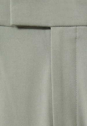 Tessuto verde chiaro con una texture liscia, caratterizzato da un design piegato e cuciture precise. Il materiale appare resistente e strutturato.